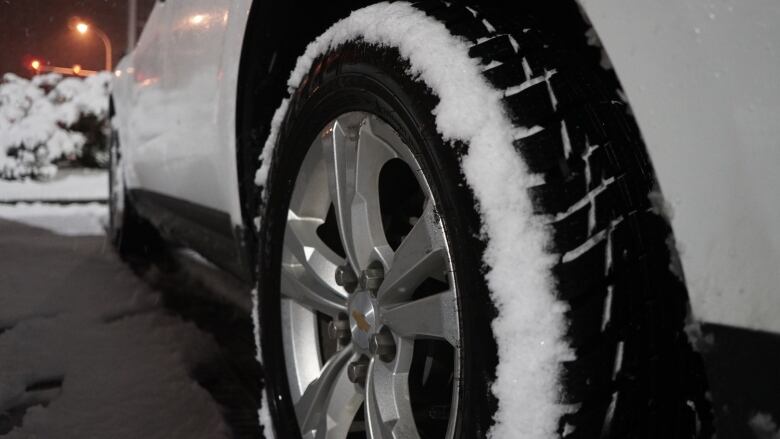 A car tire up close shows snow on its treads.