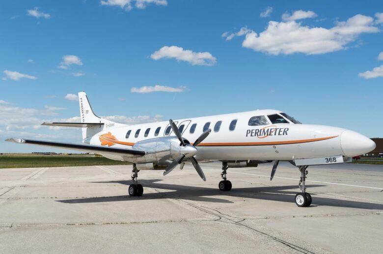 A two-propeller small air craft sits parked at an air field. 