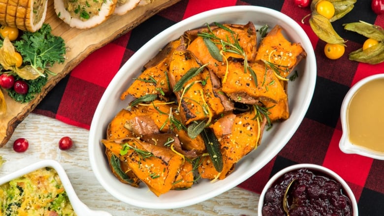 An overhead shot of a dish with roasted sweet potatoes topped with fresh herbs.