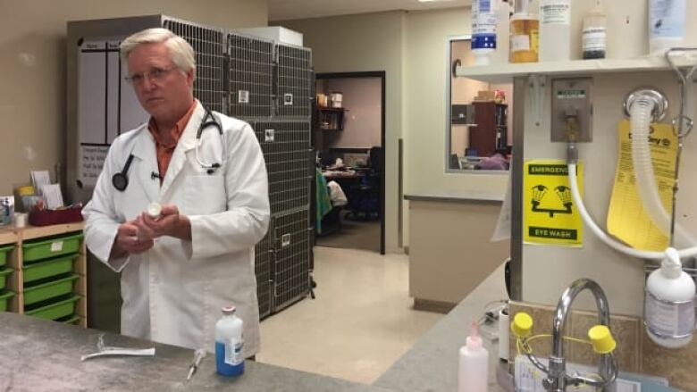 A man in a white coat prepares medication.