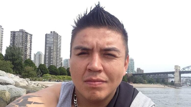 Portrait of a man with black, spiked hair on a beach.