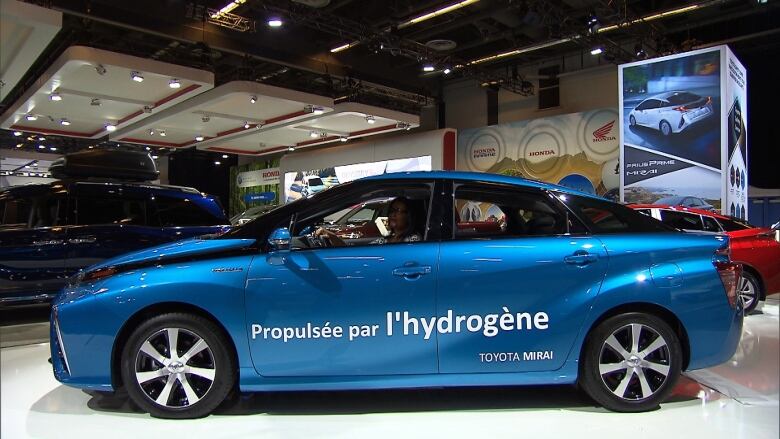 A blue vehicle with French lettering sits in an auto show.