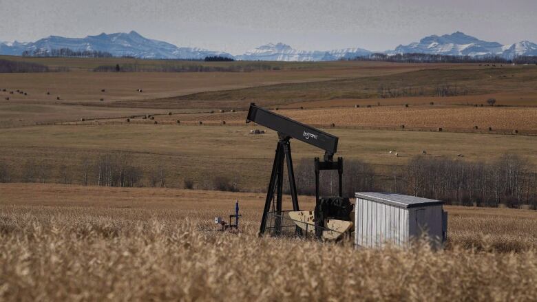 A pumpjack against a mountain backdrop.