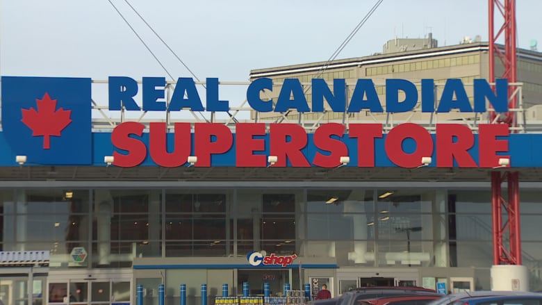 The entrance to a grocery store is seen from the parking lot. The name, Real Canadian Superstore, is visible above the entrance.