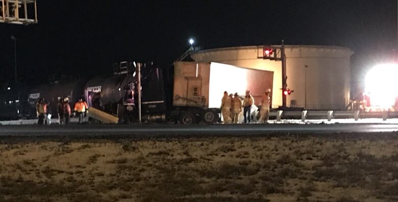 Damaged semi truck with people trying standing around it.