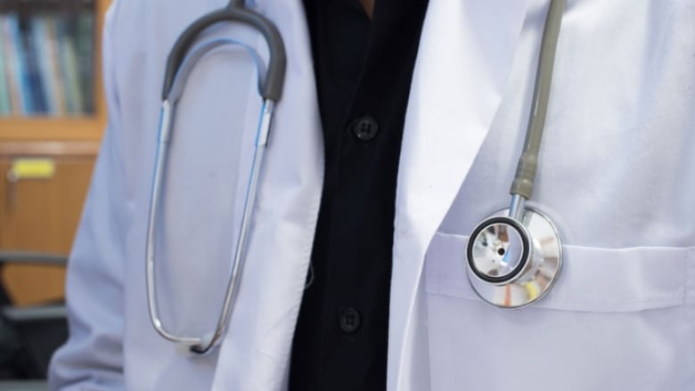 A person is wearing a white doctor's coat and a stethoscope. Only their body is visible.