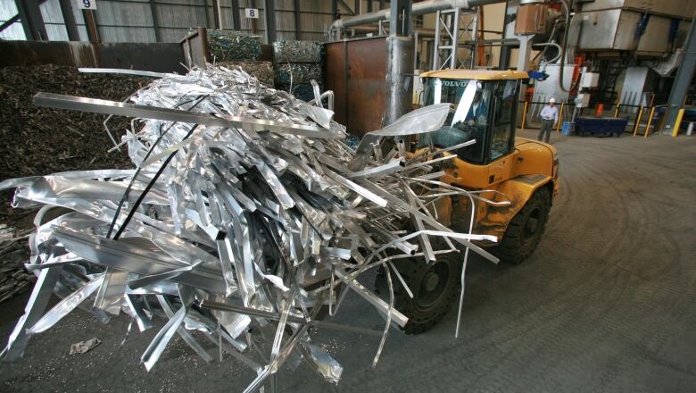 A forklift is carrying strips of aluminum across a factory floor in a new remelt plant.