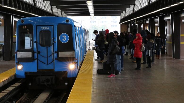 Blue light rail car sits in the station.