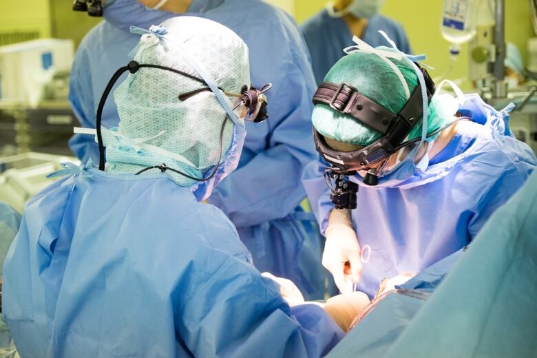 Doctors wearing medical scrubs are shown inside of a hospital room.