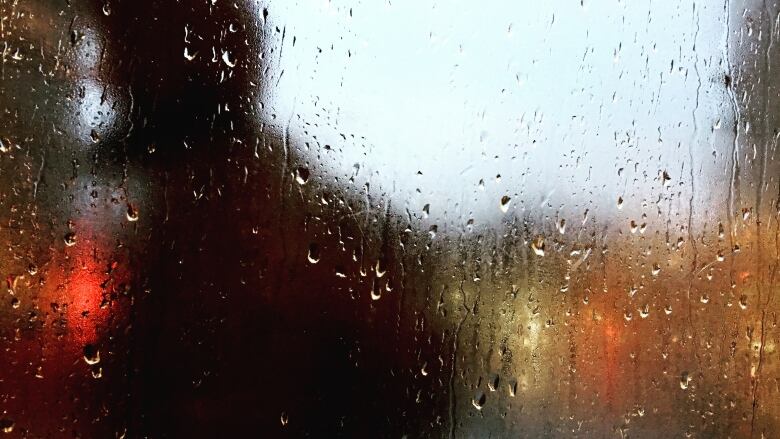 A person walks by a window with rain dripping down.