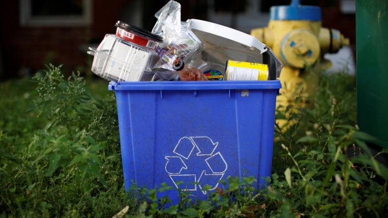 An overfilled recycling blue box. 