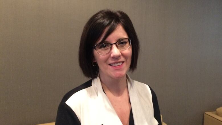 A woman wearing glasses and a black and white blouse.