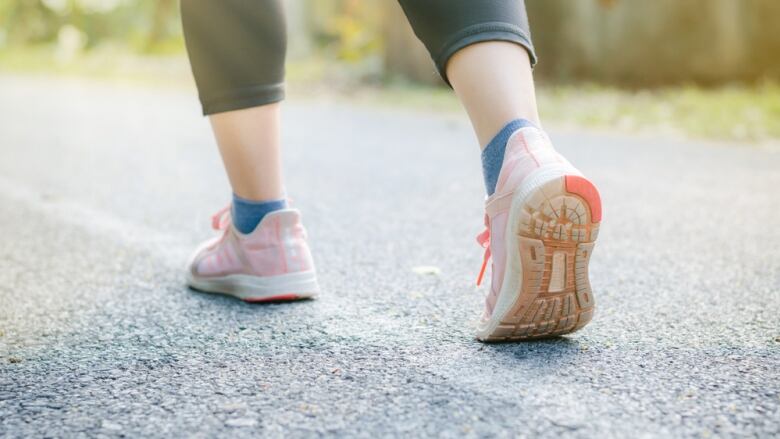 A woman's feet are seen upclose in running shoes while going down a street.