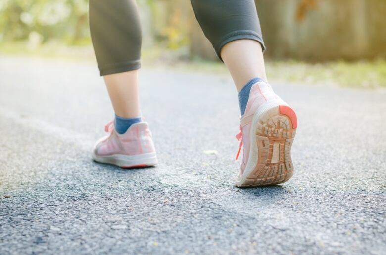 A woman's feet are seen upclose in running shoes while going down a street.