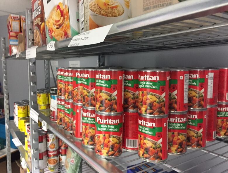 Rows of canned food sits on metal shelves.