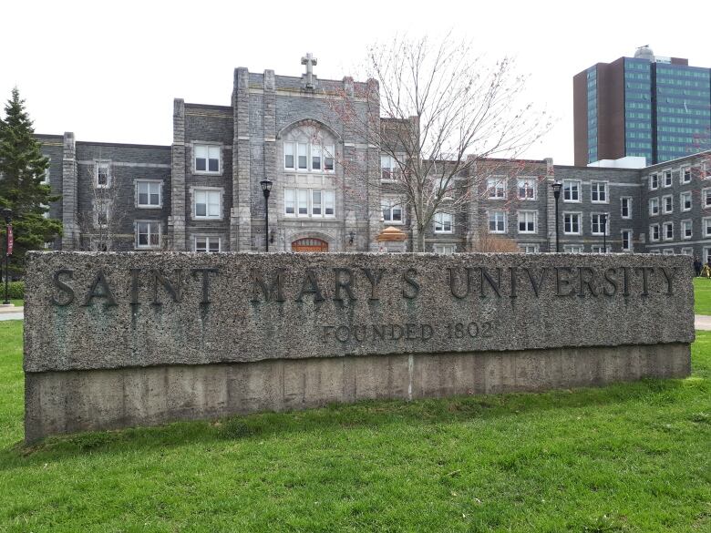 A large stone university building stands behind a large concrete sign for Saint Mary's University. 