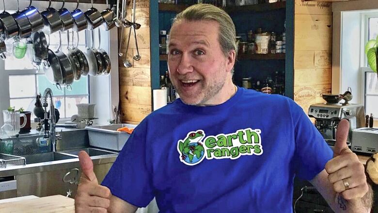 Smiling man in purple T shirt shown in a kitchen. 