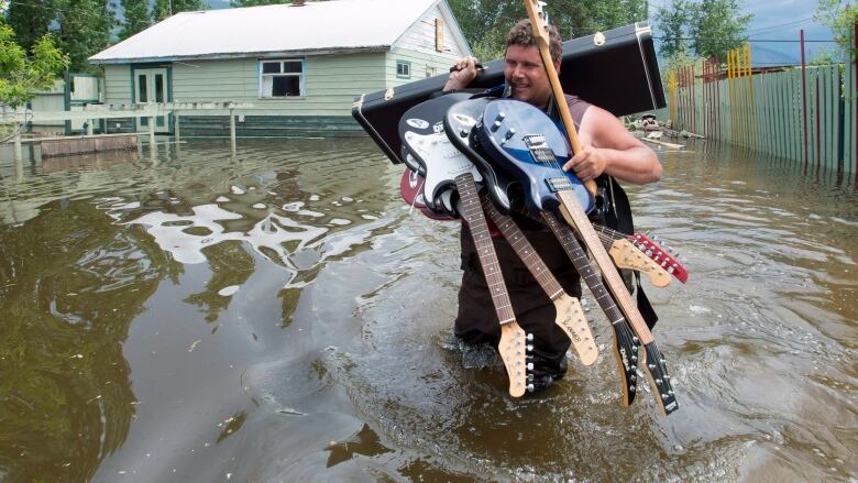 A man carries guitars through a flood,