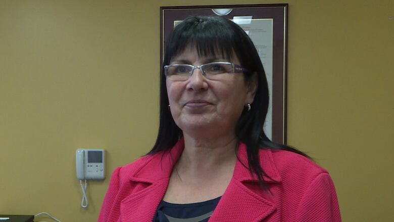 A smiling woman wearing a pink blazer.