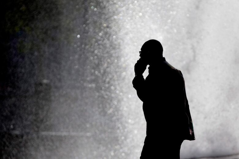 A silhouetted man talks on his cellphone.