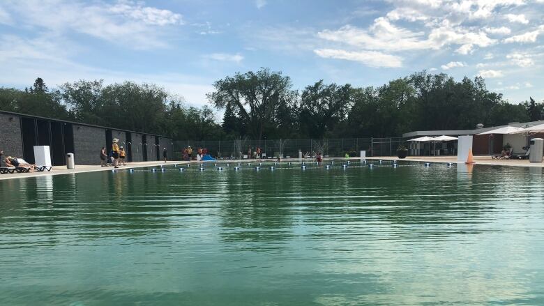 A lifeguard stands beside a pool filed with blue green water.