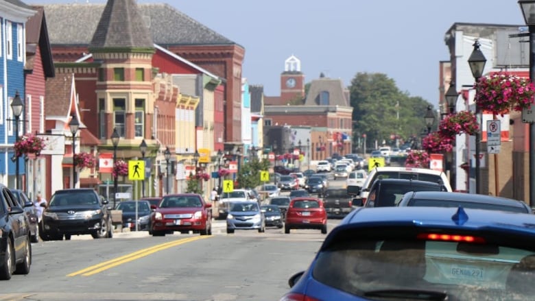 A busy downtown street is full of cars on a sunny day.