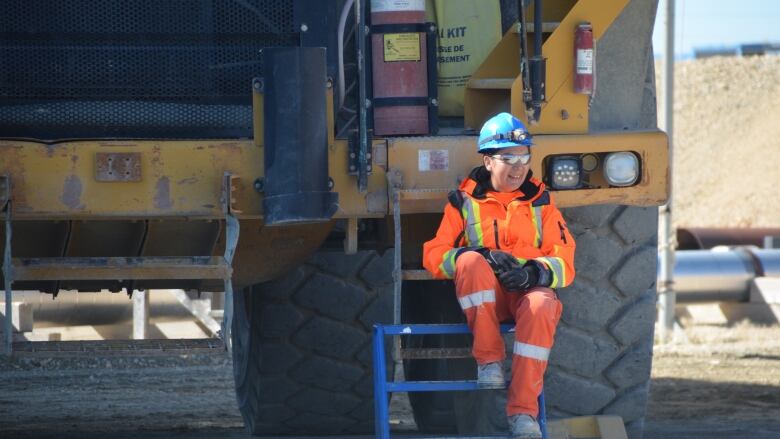 A mining worker sitting next to a truck.