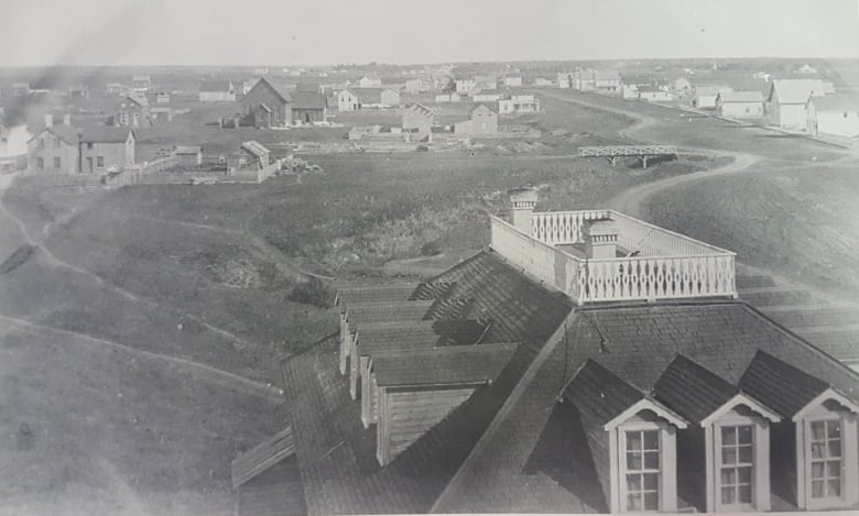 Old black and white photo shows a sparse collection of buildings on an open expanse of land.