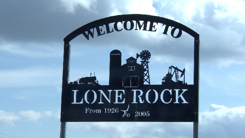 A metal signs shows a farm house, pump jack with the words 