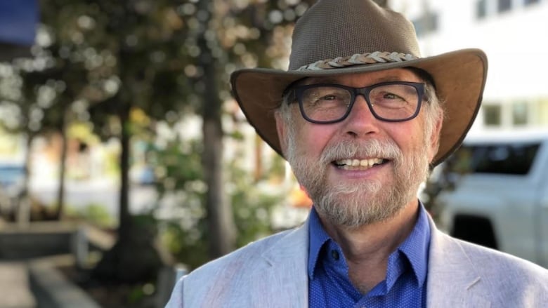 A smiling man wearing a suit and a cowboy hat