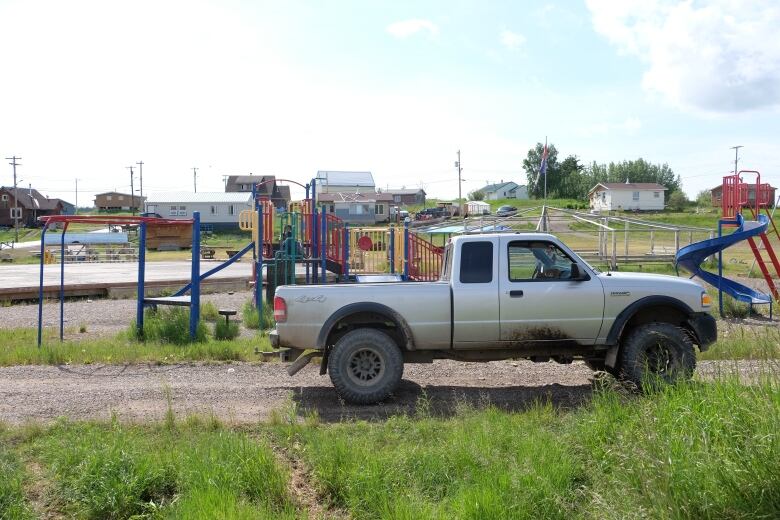 A truck stands before a playground on a sunny day.