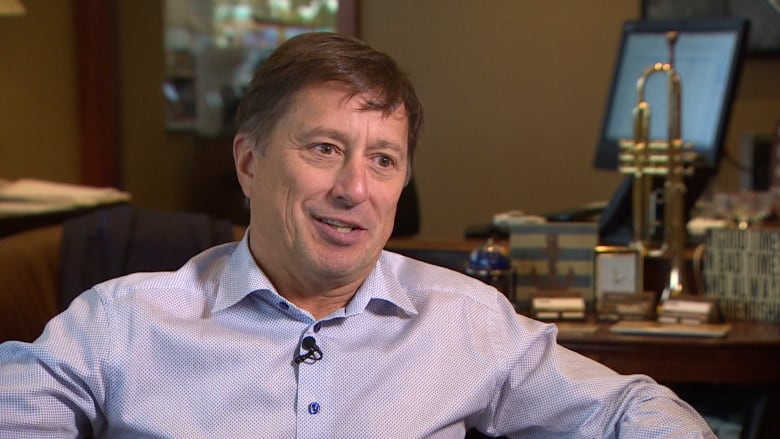 A man in a purple dress shirt sits in an office. 