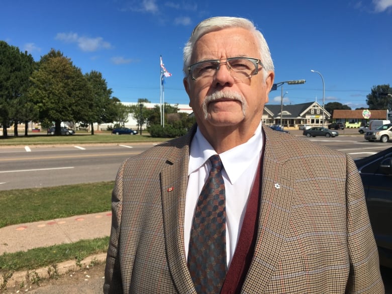 A man in a plaid suit standing in a parking lot.