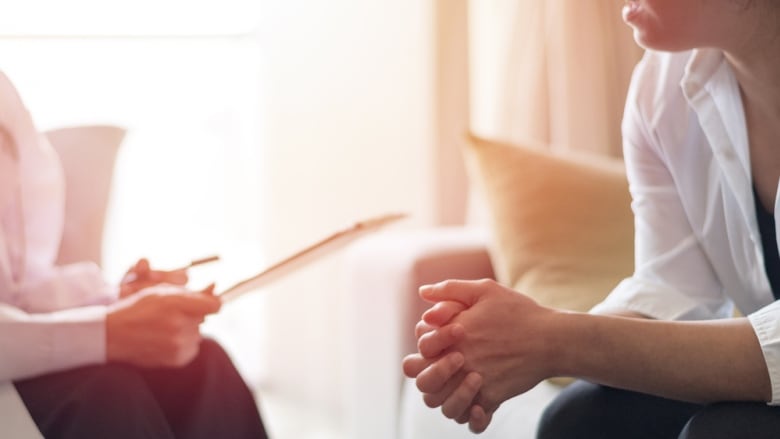 A stock photo shows a woman speaking with a therapist.