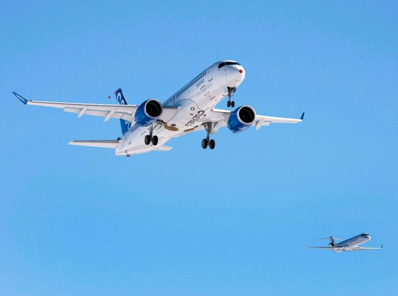 Two jets fly overhead in a blue sky. 