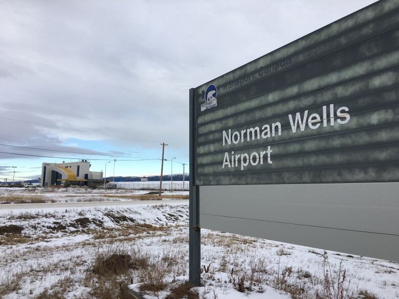 A large sign near a road reads, 'Norman Wells airport.'