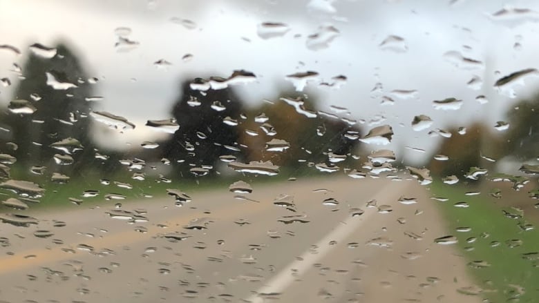 A road as seen through a windshield covered with rain.