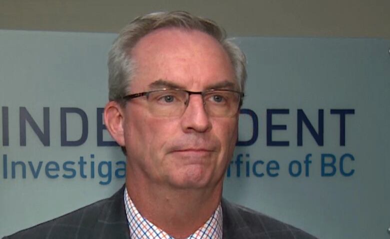 A white man speaks in front of a sign reading 'Independent Investigations Office of BC'.