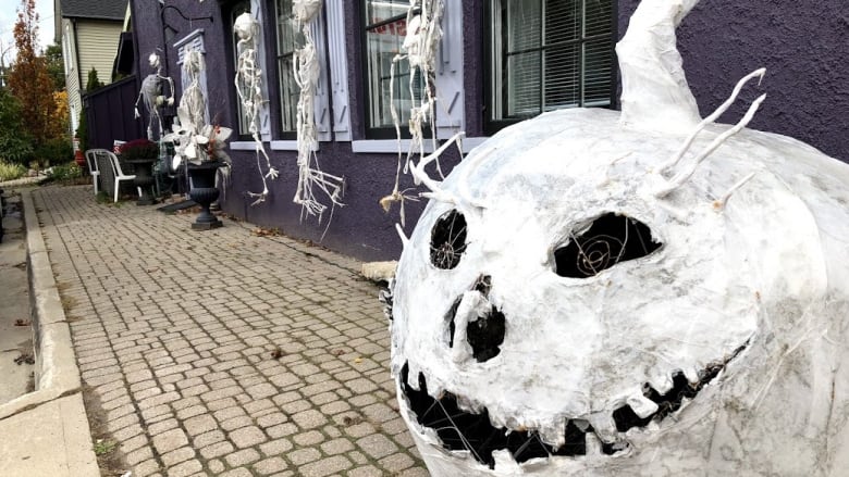 A very large white pumpkin made of gauze and wire sits on a sidewalk