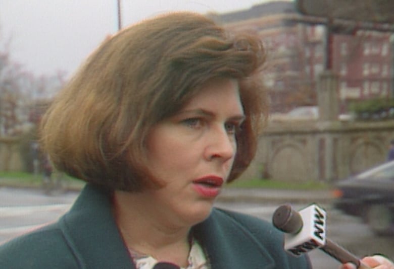 Gloria Lemay is shown speaking to reporters in an archived image taken from video. She wears her hair in a brown bob and has a dark green coat.