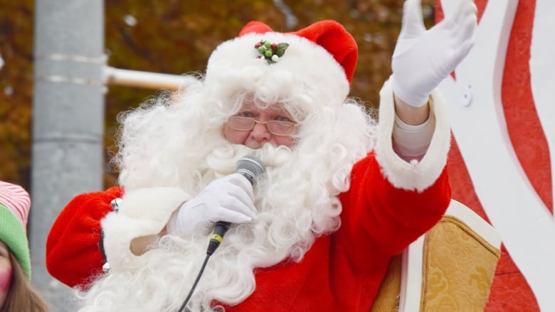 Santa waves to people during a parade