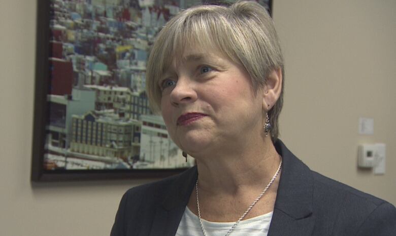 A woman with short hair and a blazer listens to a question. 