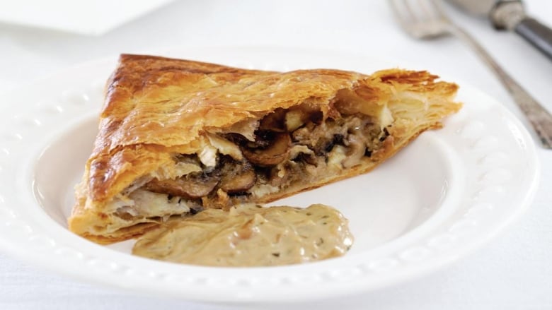 A slice of mushroom and brie pie on a white plate.