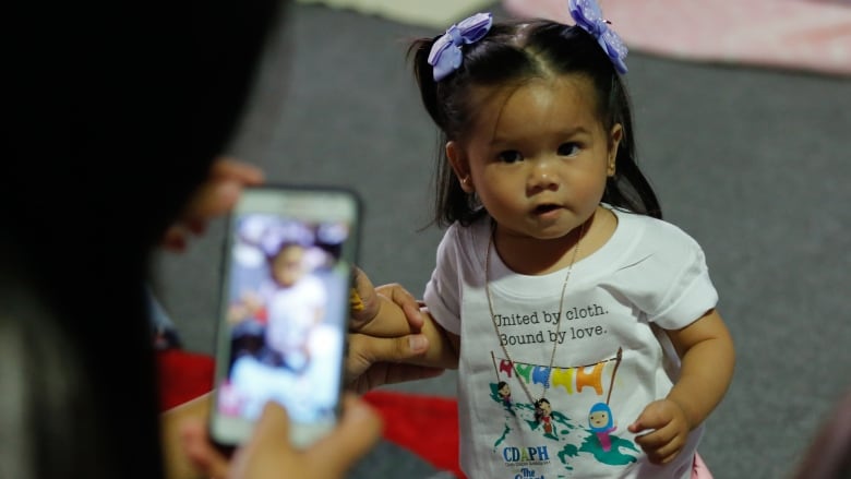 A Filipino mother takes a picture of her daughter wearing a cloth diaper during the 'Great Cloth Diaper Change' in Pampanga, north of Manila, Philippines