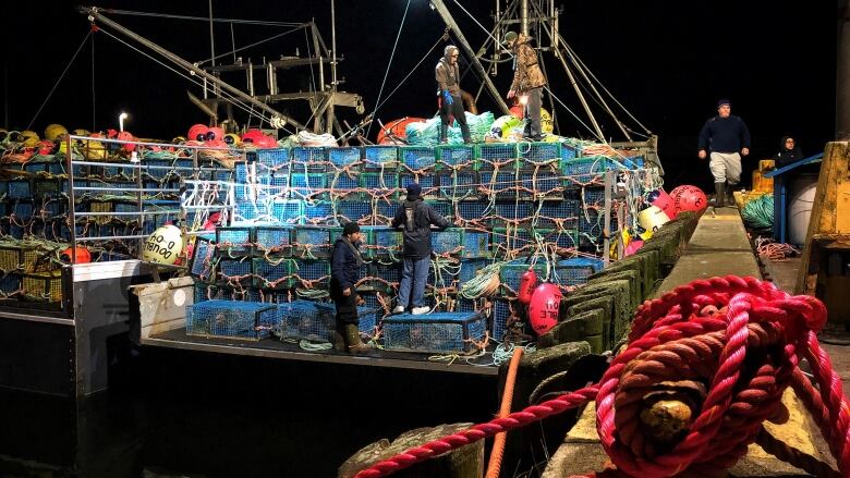 boats and lobster traps tied up in a dock in the dark.