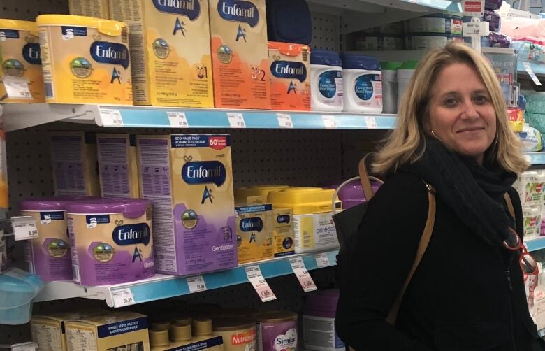 A woman standing in a grocery store aisle with baby formula.