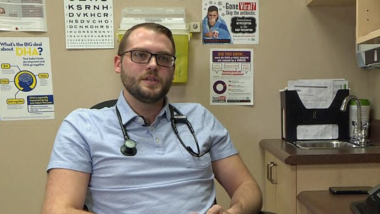 Man in blue collared shirt with glasses sits in doctors office.