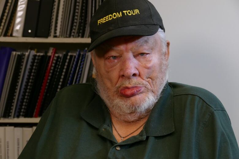 Old man with grey beard, wearing a ball cap.