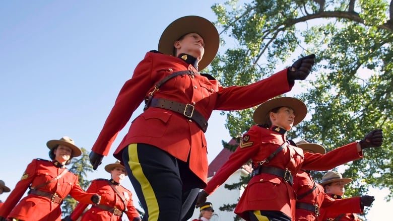 Rows of RCMP officers march while wearing their Red Serge uniforms. 