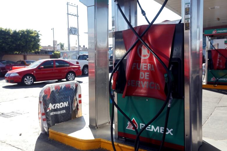 A gas station dispenser with a red blanket on it, reading 'out of order' in Spanish.